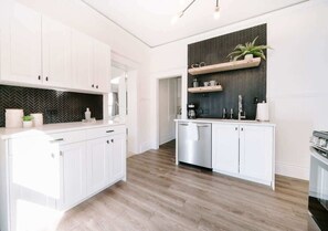 A modern kitchen with white cabinetry, a herringbone-patterned backsplash, and a wooden floor. - Olde Town Ambler A Distinctive Walkable Retreat (Arvada)