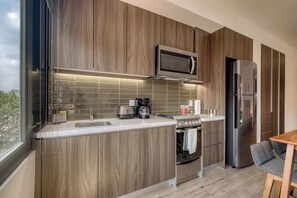 Eine moderne Küche mit Holzschränken, einem Edelstahlkühlschrank, einer eingebauten Mikrowelle und einem Gasherd.