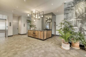 A reception area with a wooden reception desk, a modern light fixture, and a large mural on the wall. - Chic Central Park Studio (Ciudad de México)