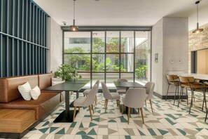 A modern interior with a sofa, dining table, chairs, and a large window offering a view of greenery. - Chic Central Park Studio (Ciudad de México)