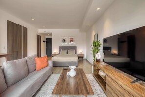 Een moderne hotelkamer met een bank, een bed, een televisie en een salontafel.