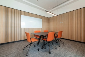 A conference room with a large table, six orange chairs, a whiteboard, and vertical wooden paneling on the walls. - Apex Executive Apartments -  Lower Kilmacud (Dublin)