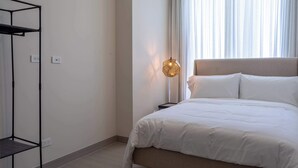 Ein Schlafzimmer mit Bett, einer Hängelampe, einem Kleiderschrank und einem Fenster mit Vorhängen.
