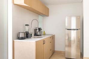 Eine moderne Küche mit einem Edelstahl-Kühlschrank, einem integrierten Mixer und einer Kaffeemaschine auf der Arbeitsfläche.