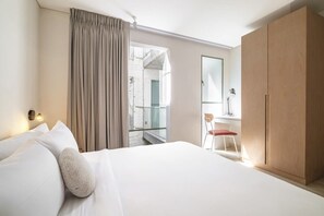 A hotel room with a bed, a chair, a wardrobe, and a view of an outdoor balcony. - CAM 1-Bdrm w Balcony (Ciudad de México)