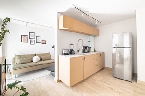 A modern kitchen with light wood cabinets, a stainless steel refrigerator, and a minimalist design. - CAM 1-Bdrm w Balcony (Ciudad de México)