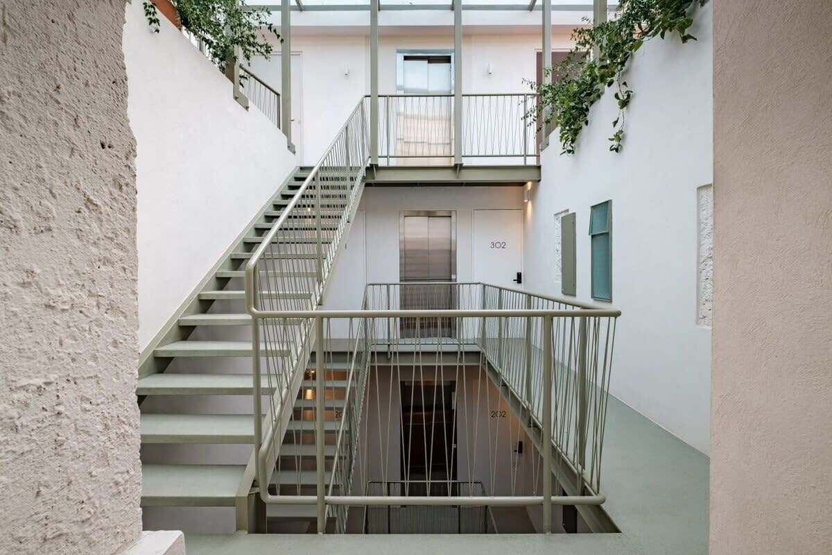 A narrow staircase with metal railings leading to an elevator.