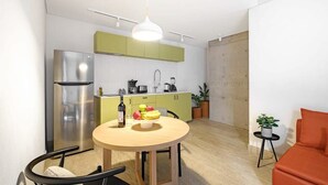 Eine kompakte Küche mit Essbereich, einem modernen Kühlschrank und einem kleinen Tisch mit Früchten und einer Flasche.