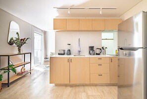 A modern kitchen with wooden cabinets, a stainless steel refrigerator, and a coffee maker. - CAM 1-Bdrm w Balcony (Ciudad de México)