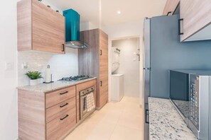 Eine moderne Küche mit Holzschränken, einem Gasherd und einem eingebauten Backofen.