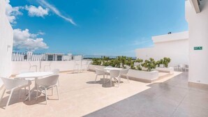 A rooftop terrace with outdoor seating and a clear view of the sky. - Cozy 1br with Balcony, Pool & Beach Access Cap Cana (Punta Cana)
