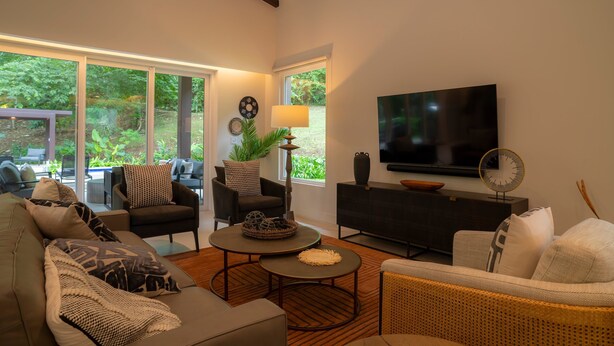 Uma sala de estar moderna com sofá, poltronas, mesa de centro e televisão.