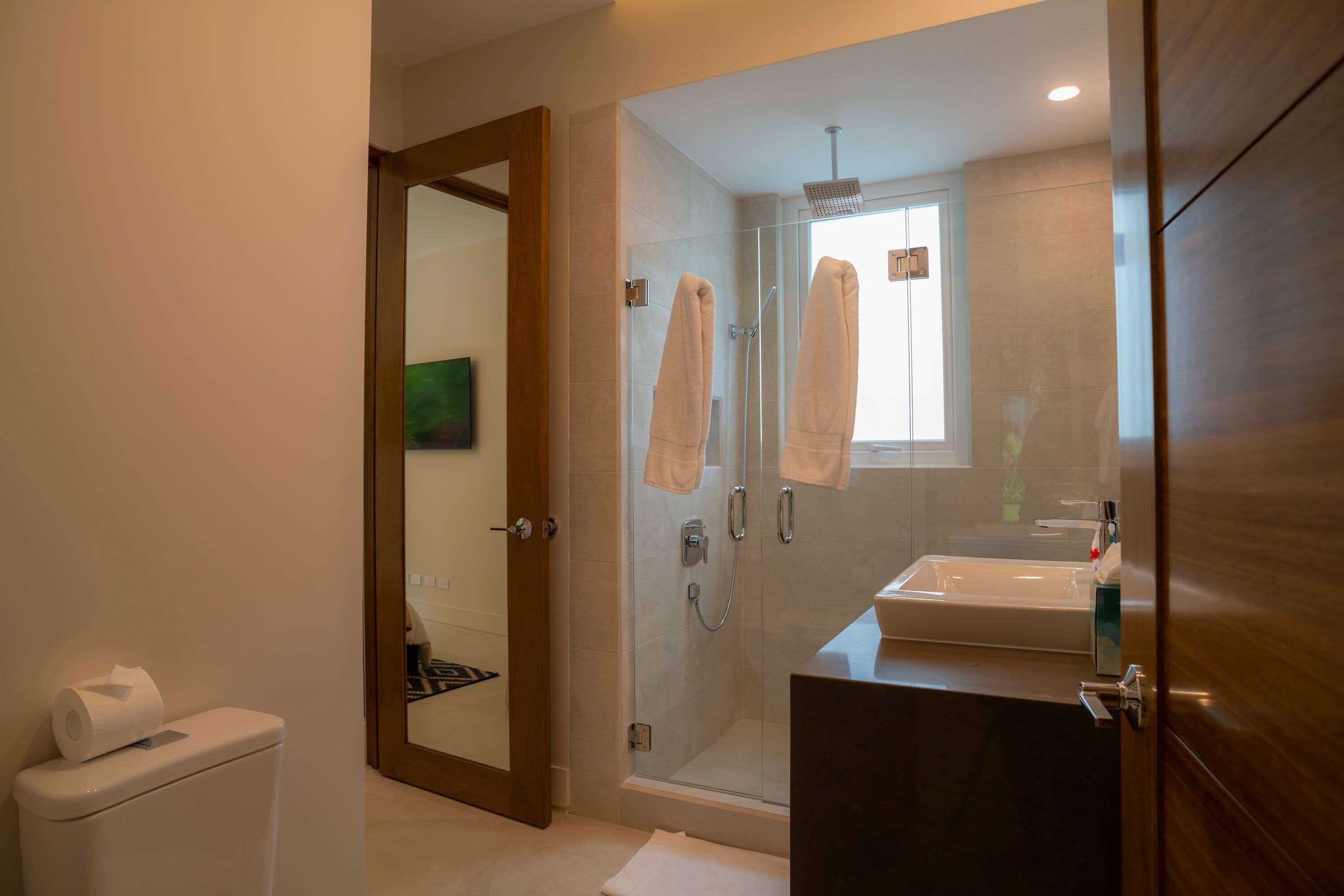 A modern bathroom with a glass-enclosed shower, a sink, and a toilet.