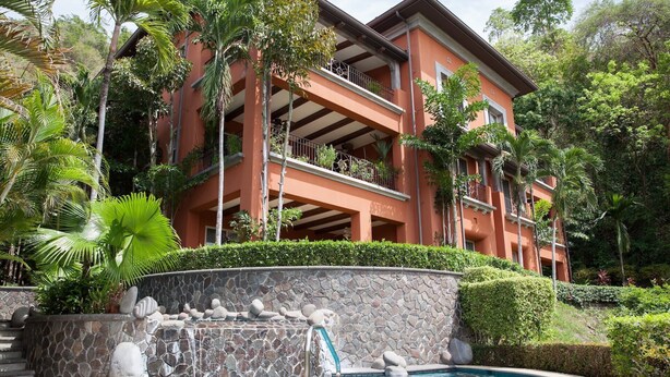A hotel with a pool, surrounded by lush greenery and a stone waterfall feature. - Montebello 1E 3 bed 3 bath, ocean view (Playa Herradura)