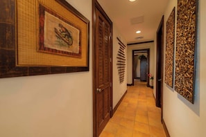 A hallway with a framed painting of a monkey, a wooden door, and a wall with vertical wooden slats. - Montebello 1E 3 bed 3 bath, ocean view (Playa Herradura)