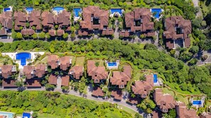 A residential area with multiple houses, each with a swimming pool and surrounded by lush greenery. - Altavista 5D 3 Bdr 2 bth Ocean View Condo (Herradura)