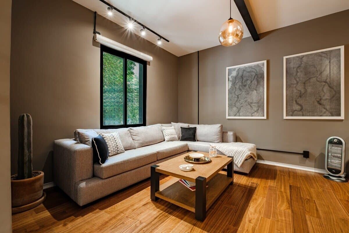 A modern living room with a sectional sofa, a wooden coffee table, and a large window providing a view of greenery.