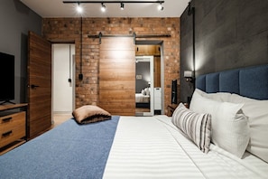 Ein Schlafzimmer mit einem Bett, einem Holzschrank, einem Fernseher und einer Ziegelwand.
