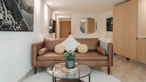 Ein modernes Wohnzimmer mit einem Ledersofa, einem Glastisch und einer Topfpflanze.
