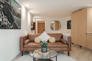 Ein modernes Wohnzimmer mit einem Ledersofa, einem Glastisch und einer Topfpflanze.