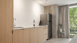 Eine moderne Küche mit Holzschränken, einem Edelstahlkühlschrank und einem Fenster mit Blick auf Grünflächen.
