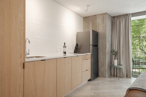Eine moderne Küche mit Holzschränken, einem Edelstahlkühlschrank und einem Fenster mit Blick auf Grünflächen.