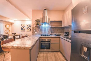 A modern kitchen with a central island, built-in oven, stainless steel appliances, and a water dispenser. - Modern flat for 3 in Piantini Gym & pool access (Santo Domingo)