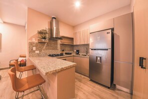 Eine moderne Küche mit Edelstahlkühlschrank, Granit Arbeitsplatte und Barhocker.