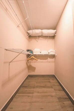 A narrow hallway with a built-in drying rack, a shelf with folded towels, and a wooden floor. - Modern flat for 3 in Piantini Gym & pool access (Santo Domingo)