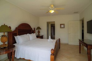 A hotel room with a large bed, a ceiling fan, a TV, and a bathroom visible through an open door. - Del Mar 3i - 3 bdr 2 bath Ocean View (Playa Herradura)