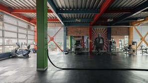 A gym with exercise equipment, large windows, and a brick wall. - Top Bed | Mixed Shared Room (Ciudad de México)
