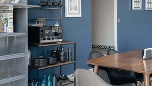 A kitchen with a microwave, shelves with plates and bowls, a table with chairs, and a framed picture on the wall. - Top Bed | Mixed Shared Room (Ciudad de México)