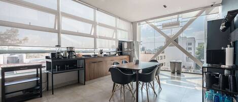 A modern kitchen with a dining area, large windows, and a view of the city.