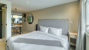 Quarto de hotel moderno com uma cama grande, mesa de cabeceira, escrivaninha e vista para o exterior.
