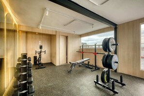 A gym with weightlifting equipment, a bench, and a mirror. - Modern King Studio in Central Roma Norte (Ciudad de México)
