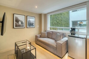 A modern living room with a sofa, a coffee maker, and framed pictures on the wall. - Modern King Studio in Central Roma Norte (Ciudad de México)