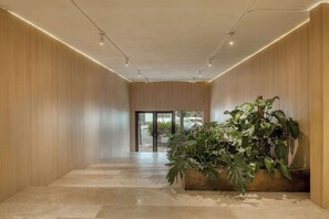 A modern hallway with wooden walls, a tiled floor, and a large potted plant. - Modern King Studio in Central Roma Norte (Ciudad de México)