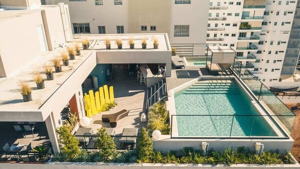 A rooftop pool area with a glass enclosure, outdoor seating, and potted plants. - Santo Domingo Oasis Modern Apartment with Amenities (Santo Domingo)