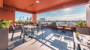 An outdoor terrace with tables and chairs, potted plants, and a city view. - Santo Domingo Oasis Modern Apartment with Amenities (Santo Domingo)
