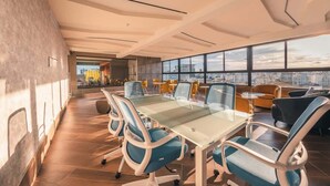 A modern conference room with a glass table and chairs, large windows with a city view, and a high ceiling with exposed beams. - Santo Domingo Oasis Modern Apartment with Amenities (Santo Domingo)