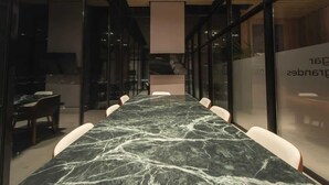 Una sala conferenze con un lungo tavolo e sedie, pareti in vetro e un moderno design del soffitto.