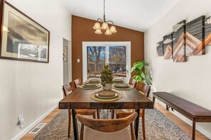 A dining room with a wooden table set for six, a bench, and a potted plant. - Family Friendly Retreat with Game Room Huge Yard (Arvada)