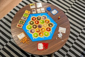 A round wooden table with a hexagonal game board, cards, and dice. - Family Friendly Retreat with Game Room Huge Yard (Arvada)