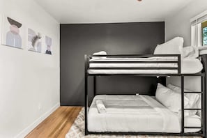 Ein Mehrbettzimmer mit dunkler Wand, weißer Bettwäsche und einem flauschigen Teppich.