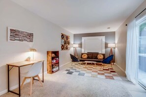 A modern living room with a desk, a sofa, a coffee table, and a large window. - Hot Tub Modern Home Great Location (Arvada)
