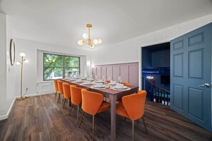 Ein Esszimmer mit einem langen Tisch, gedeckt für sechs Personen, Holzboden und einer blauen Tür.