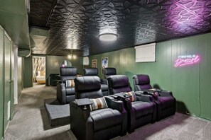 Ein Zimmer mit einer grünen Wand, einem Neonzeichen und einer Reihe schwarzer Ledersessel.