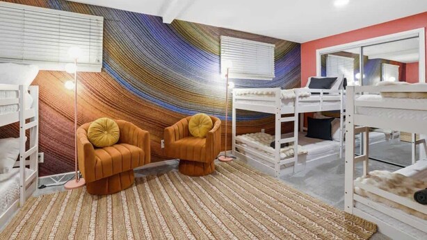 Quarto com beliches, sofá e um grande mural na parede.