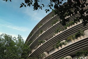 Een meerlaags gebouw met balkons, waarvan sommige beplant zijn.