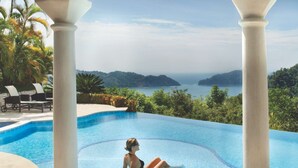 A pool with a view of the sea, surrounded by columns and palm trees. - Casa Puesta del Sol 5 bdr - Ocean View Family (Playa Herradura)